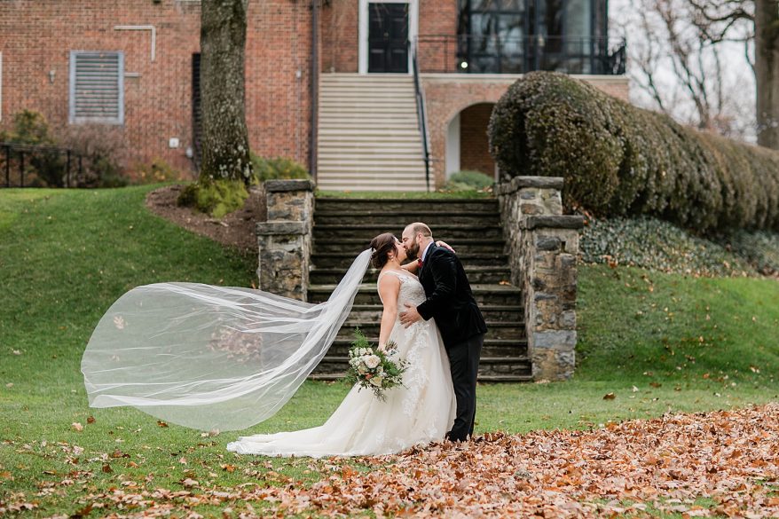 couple kisses under fall leaves at Baltimore country club