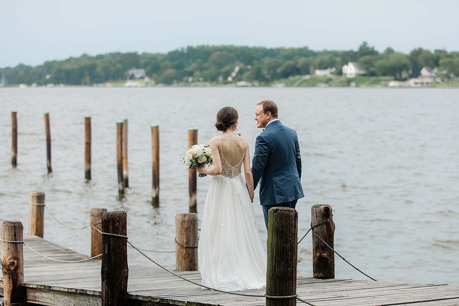 newlyweds walk on dock over water by Baltimore wedding photographer