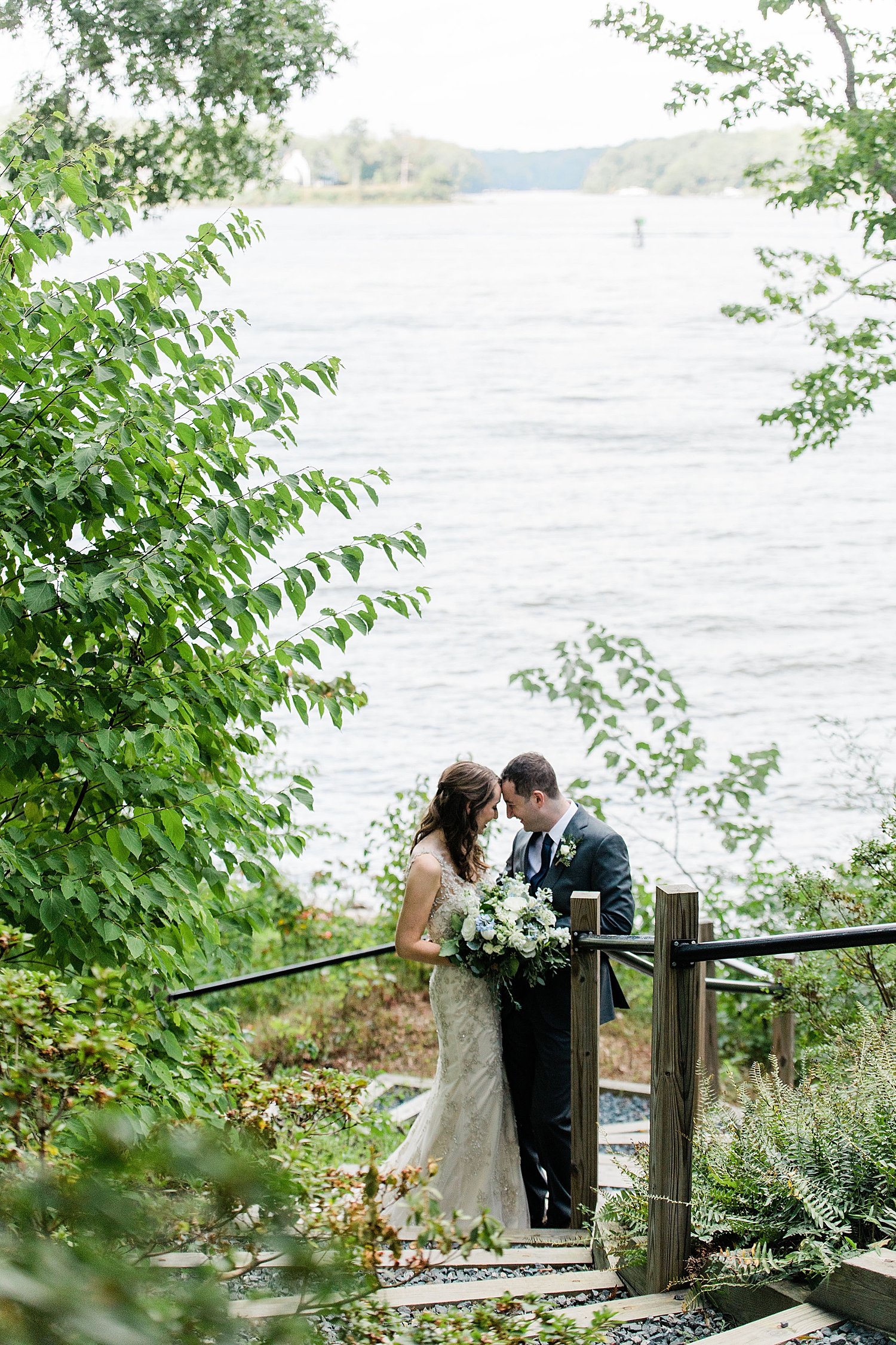 husband and wife share a private moment on stairs outside overlooking water by Baltimore wedding photographer