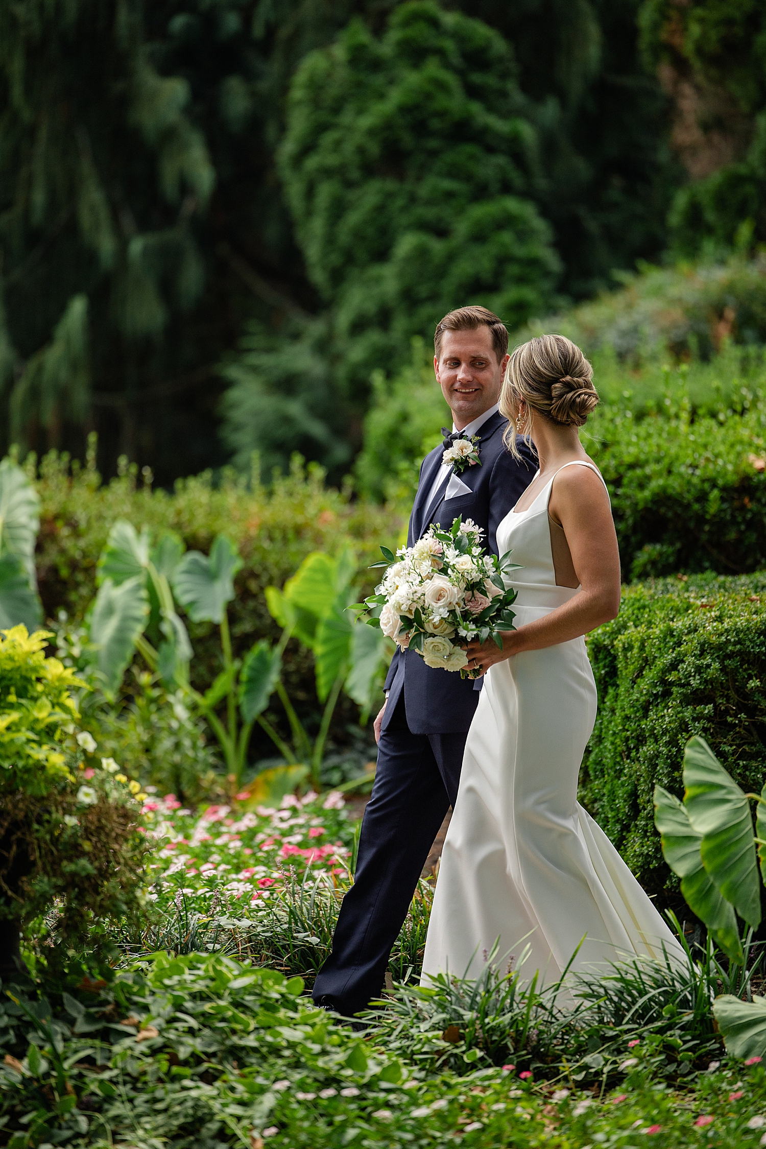 newlyweds stroll through lush, green garden by Baltimore wedding photographer