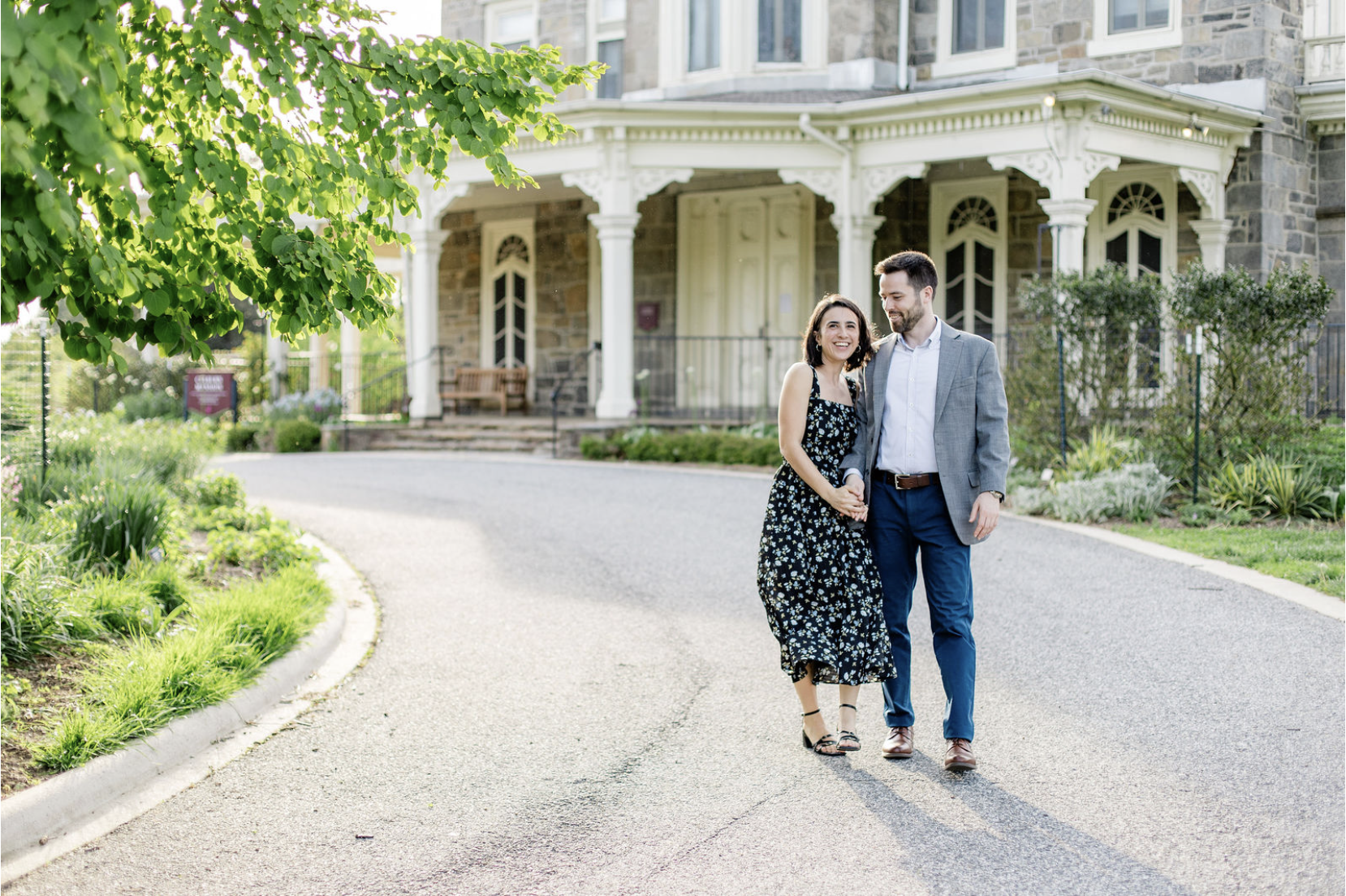 couple walking hand in hand in front of historic mansion in spring