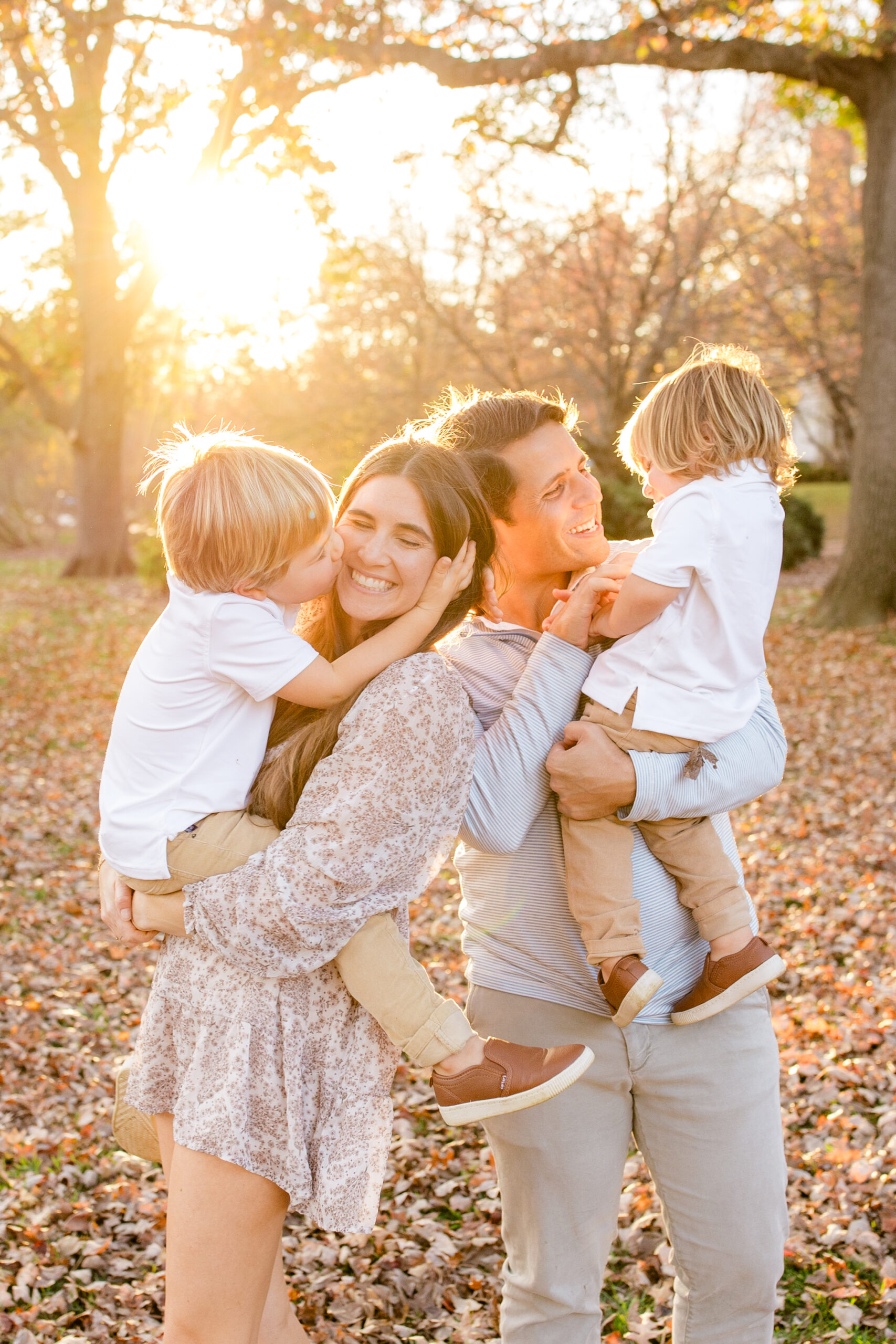 smiling baby with parents and sibling during a candid autumn family photoshoot in a park
