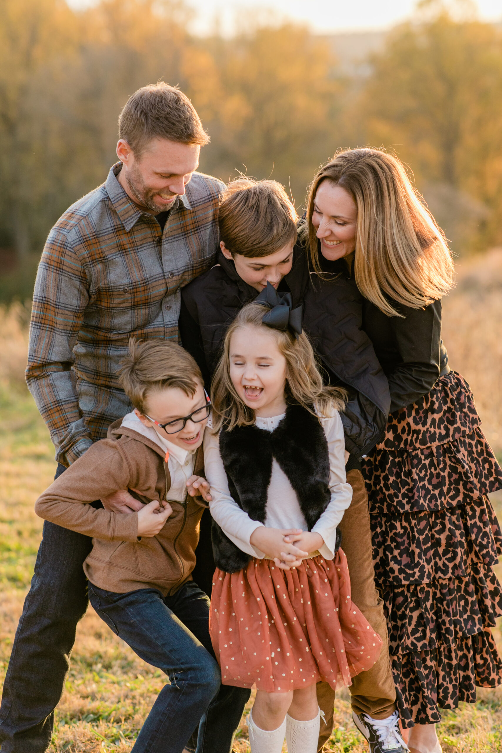 parents hugging toddlers during a golden hour family session with coordinated neutral outfits