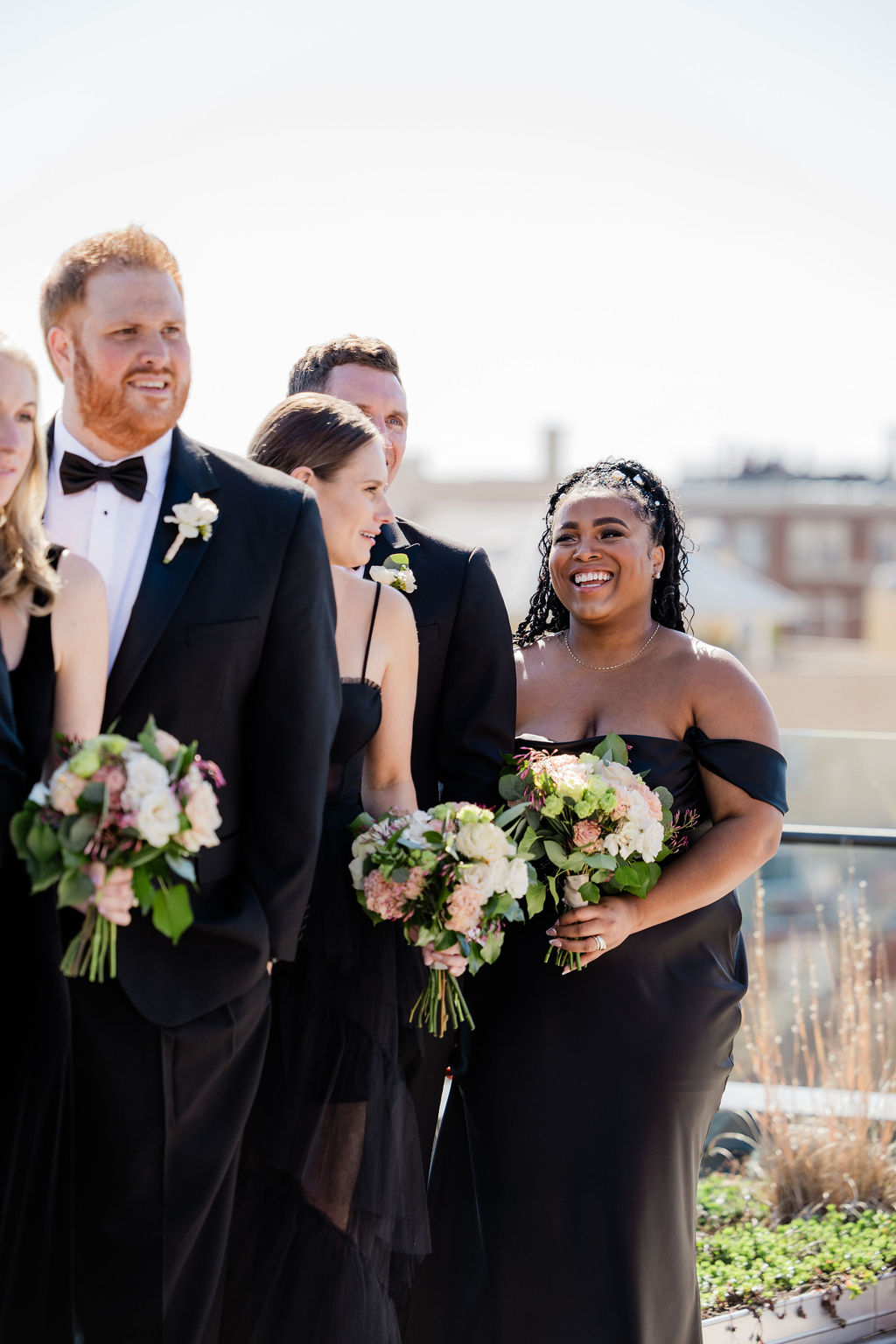 bridesmaids and groomsmen in classic black attire during rooftop wedding portraits