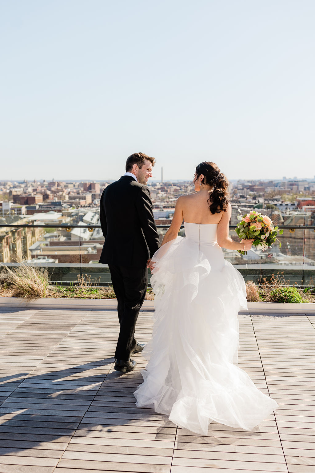 bride and groom walking on rooftop terrace overlooking washington dc skyline 