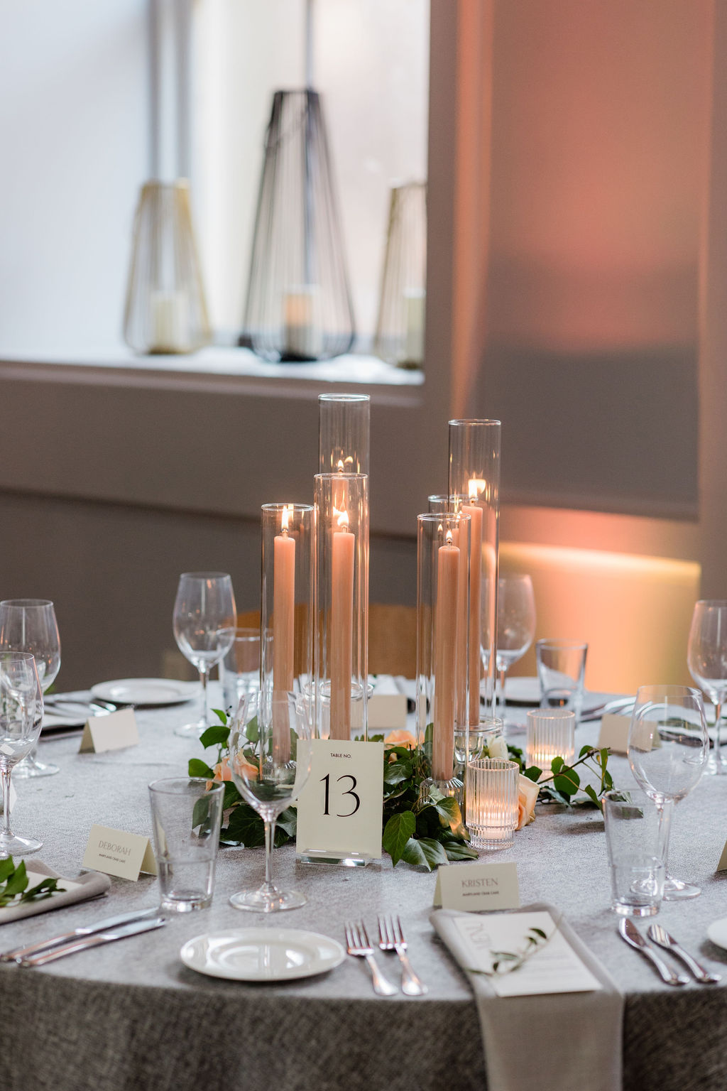 candlelit wedding table centerpiece with tall glass votives and greenery for a romantic reception design