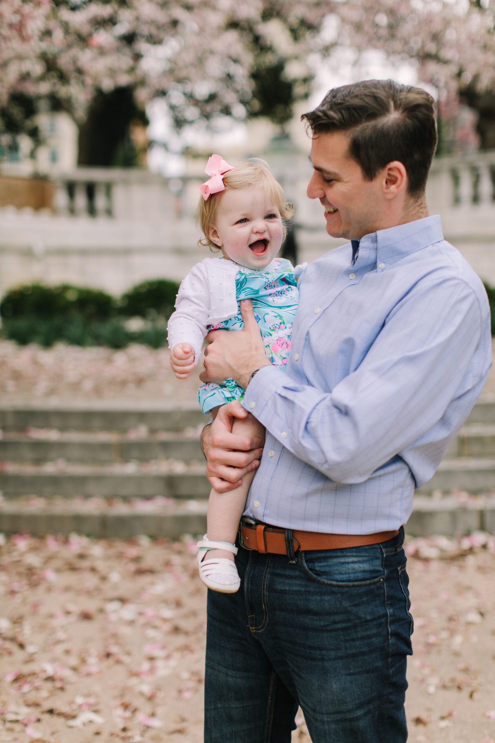 father holding smiling baby girl with soft floral background