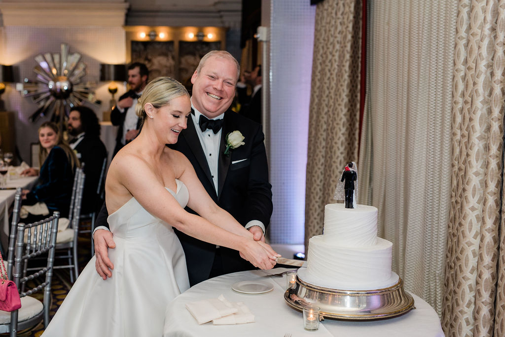 couple cutting their wedding cake together during reception celebration