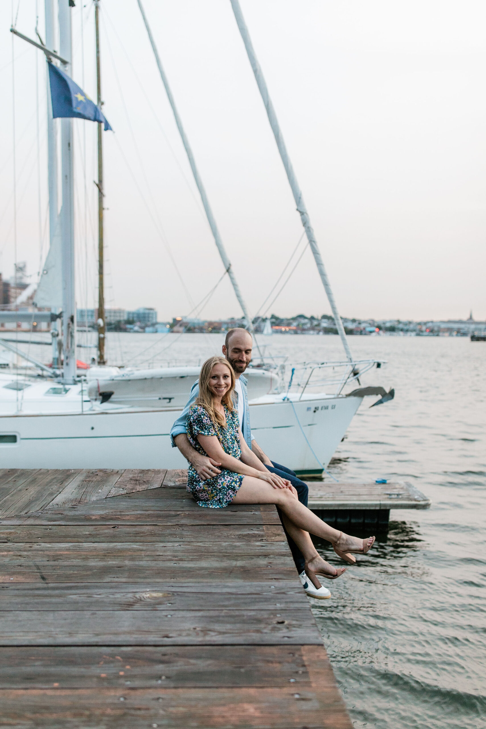 Couple sitting on dock during a waterfront engagement session at one of the most popular engagement photo locations in Baltimore