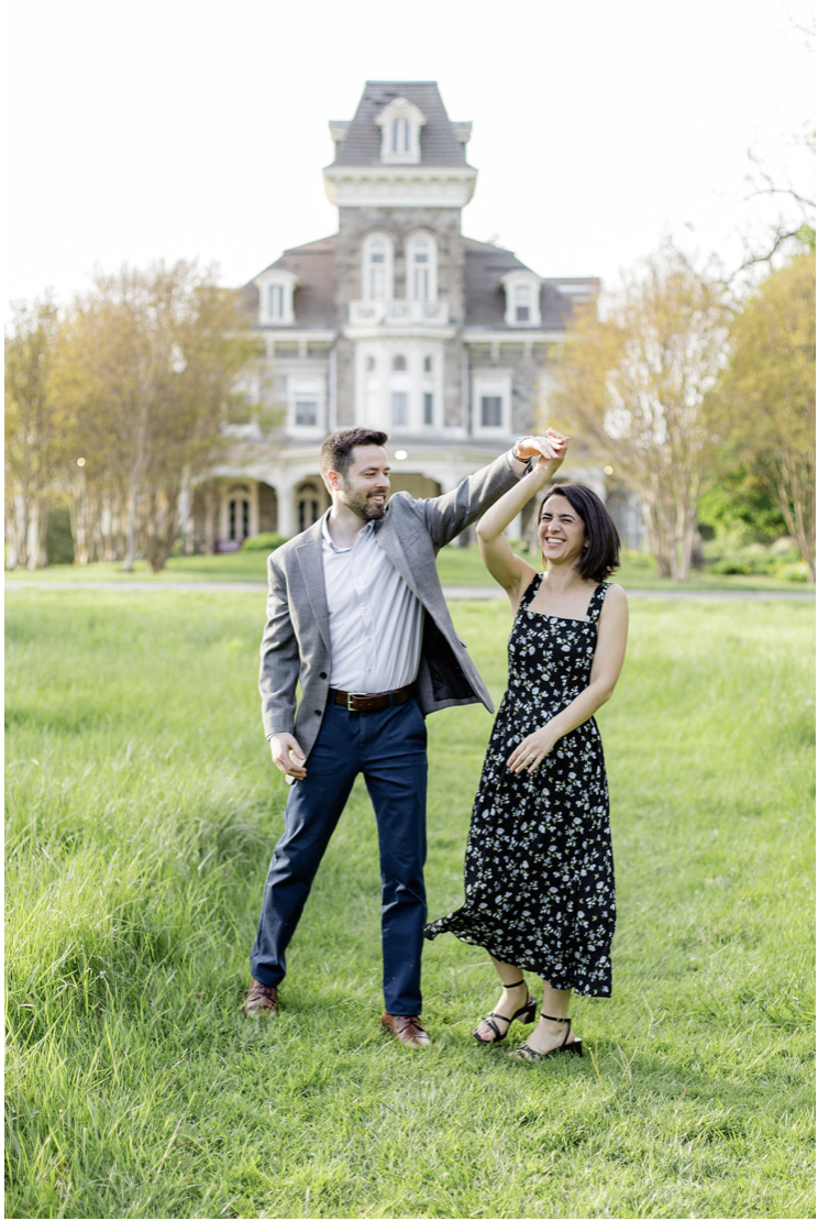 Playful engagement photo pose in front of Cylburn Arboretum mansion with romantic spring ligh