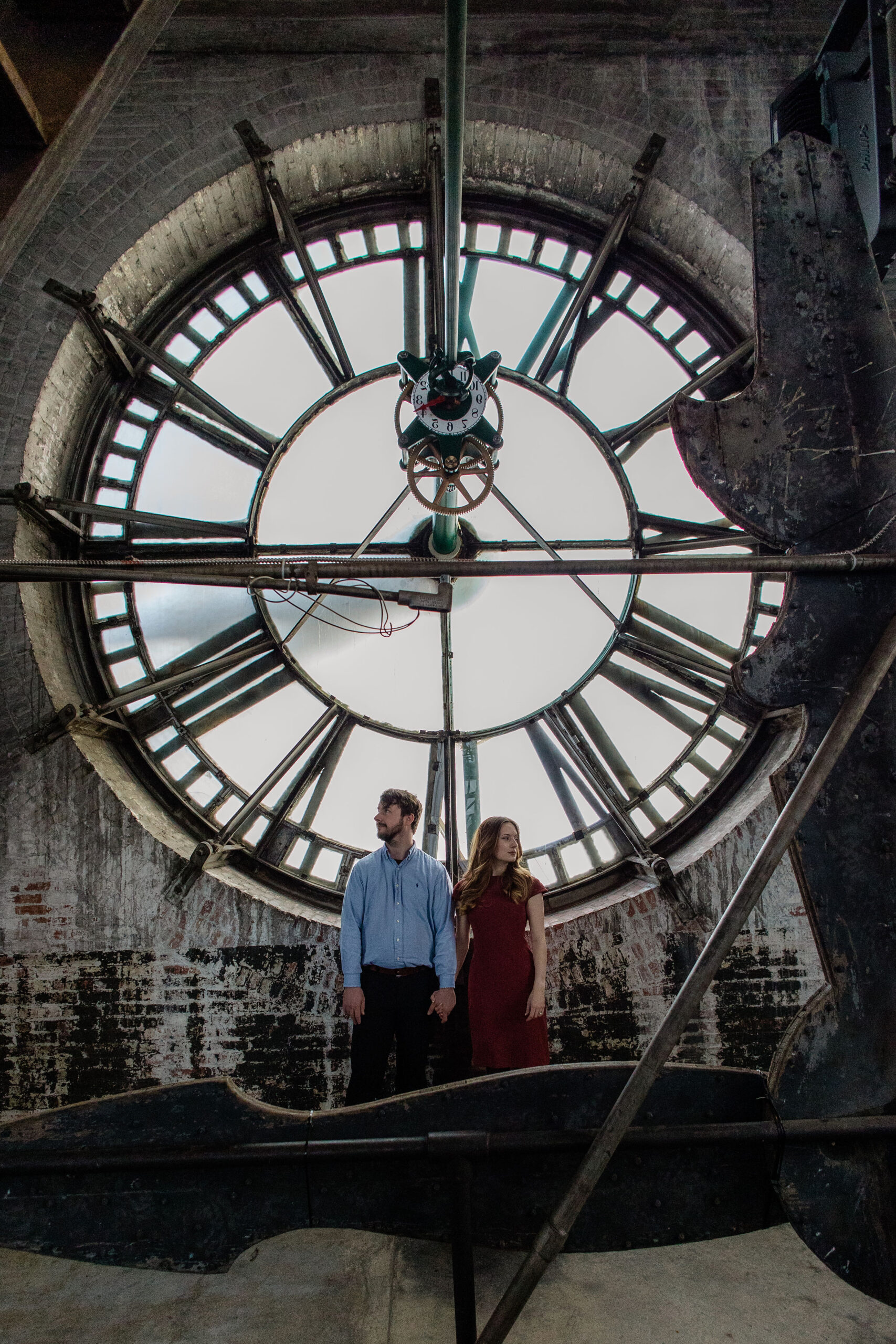 Romantic couple standing beneath the clock face inside the Bromo Seltzer Tower, a dramatic Baltimore location for engagement photos