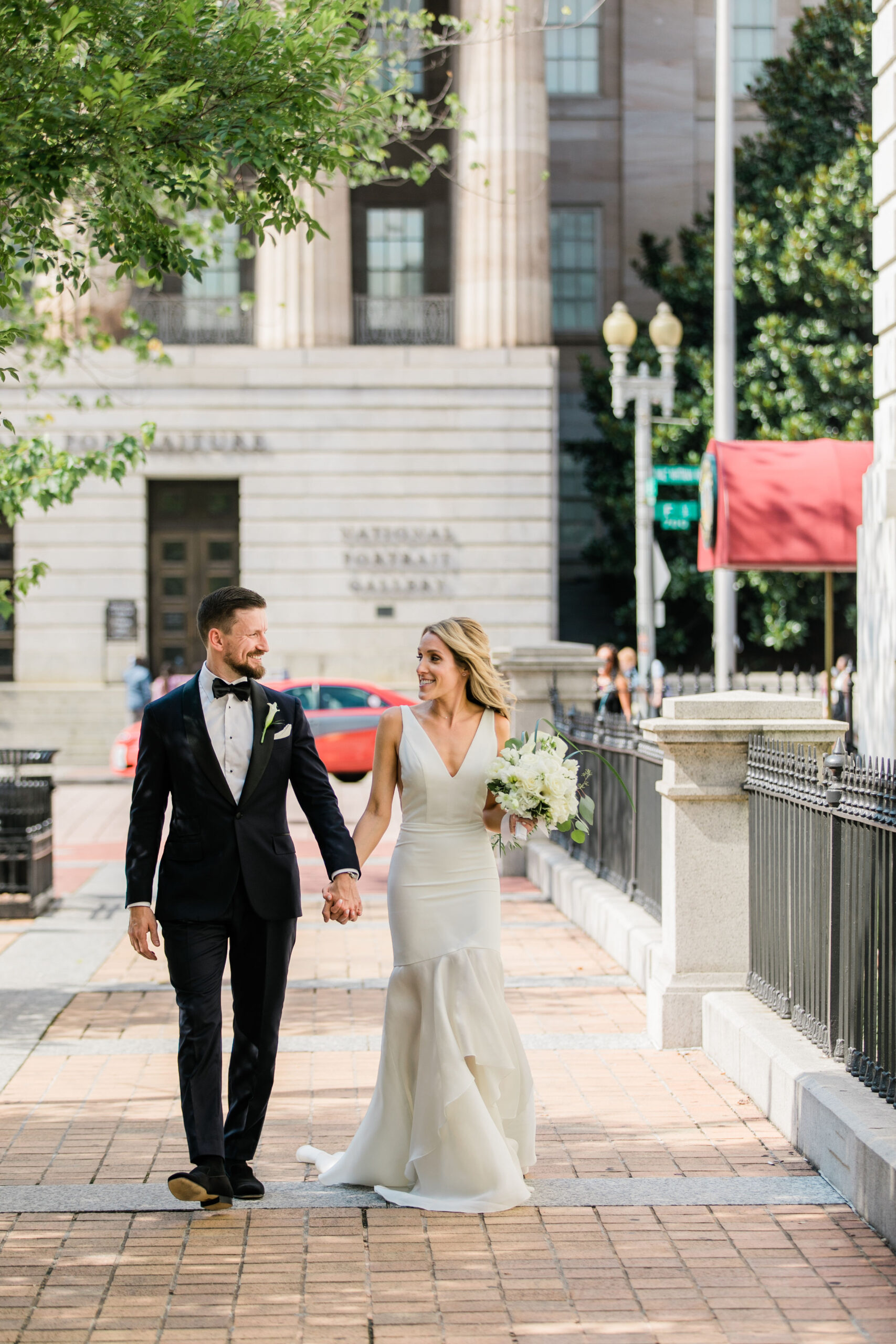 bride and groom walking hand in hand on washington dc street with classic architecture backdrop
