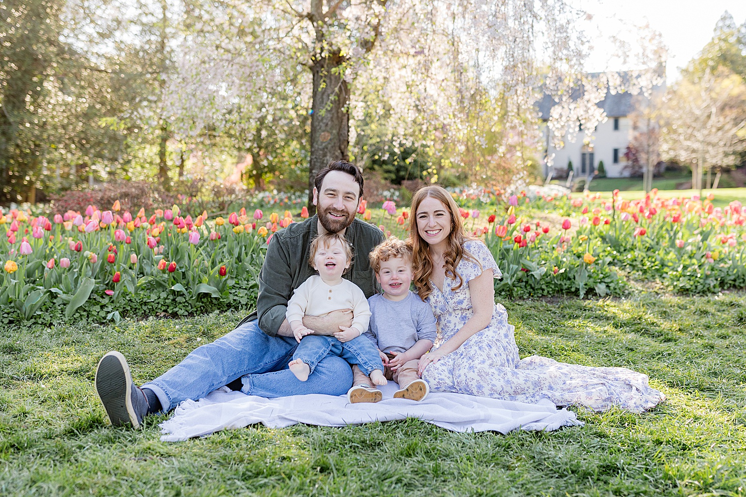 family of four sits on grass in Sherwood Garden documenting young families