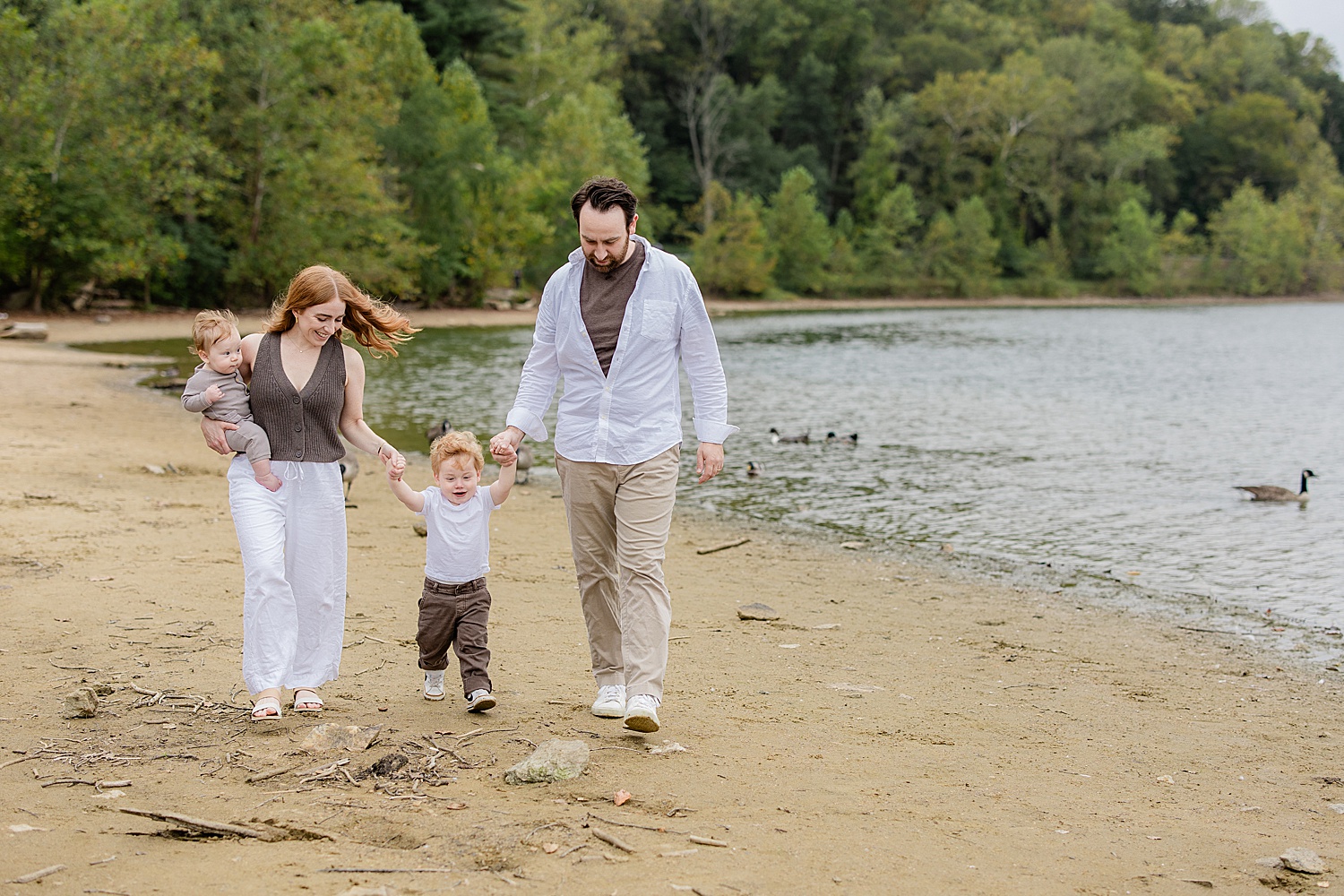 parents hold hands with small toddler by Baltimore family photographer