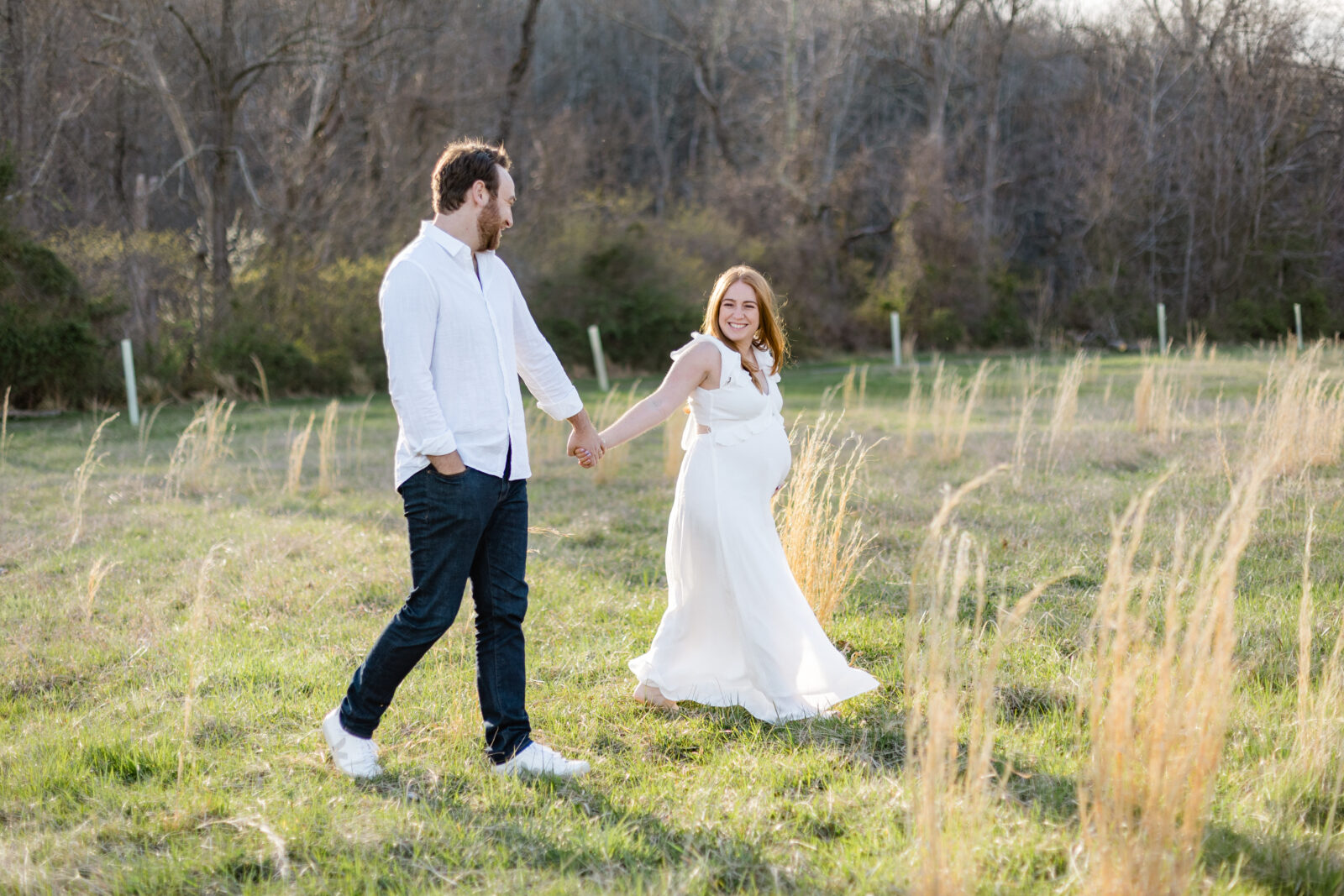 A couple in a field during their maternity session captured by a Baltimore family photographer.