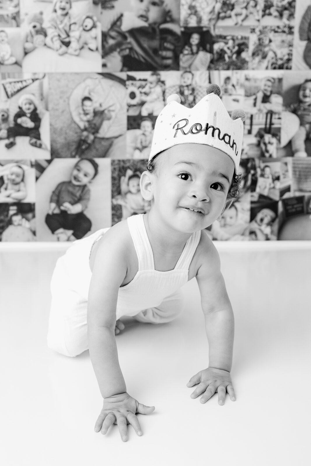 One-year-old child in front of collage of baby photos