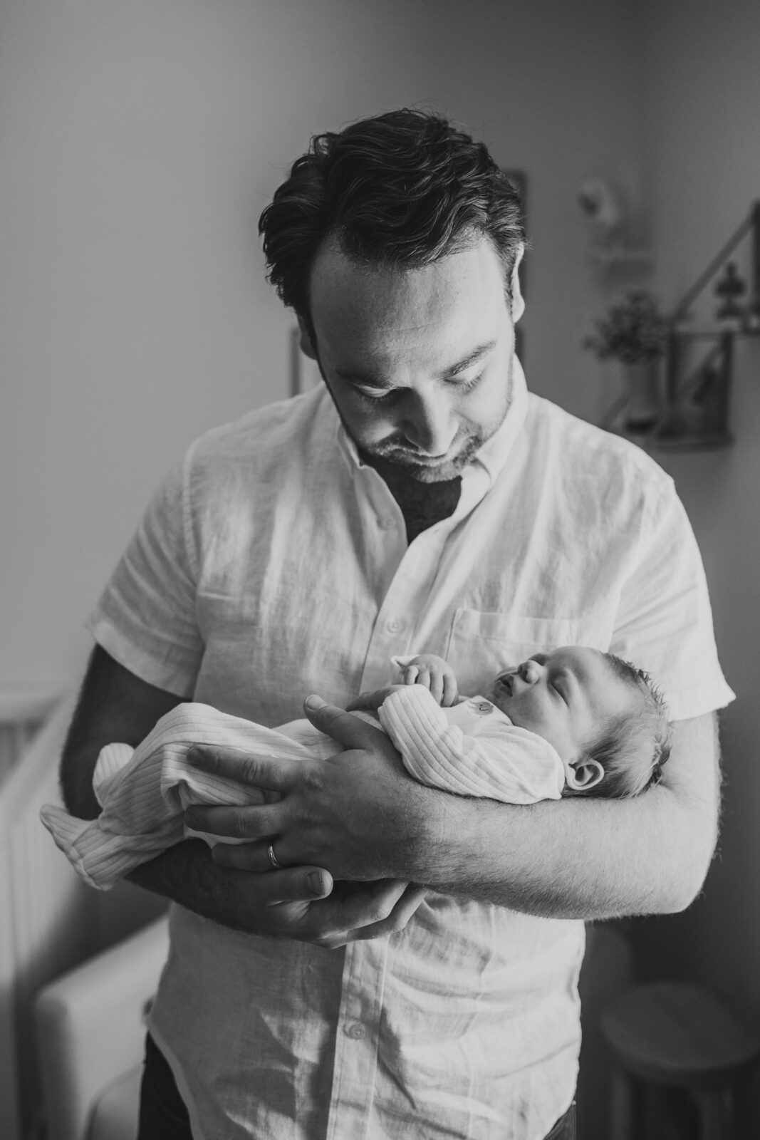 Black and white photo of a dad with a newborn baby.