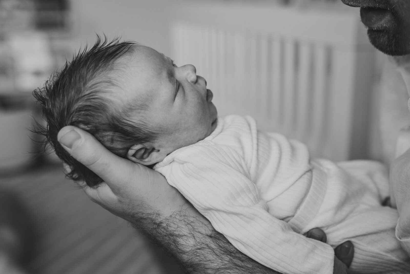 A black and white photo of a newborn son being held by his dad captured by a Baltimore family photographer.
