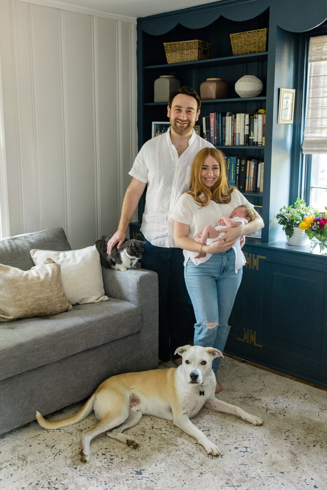 A family of three holding their newborn son with their dog laying at their feet.
