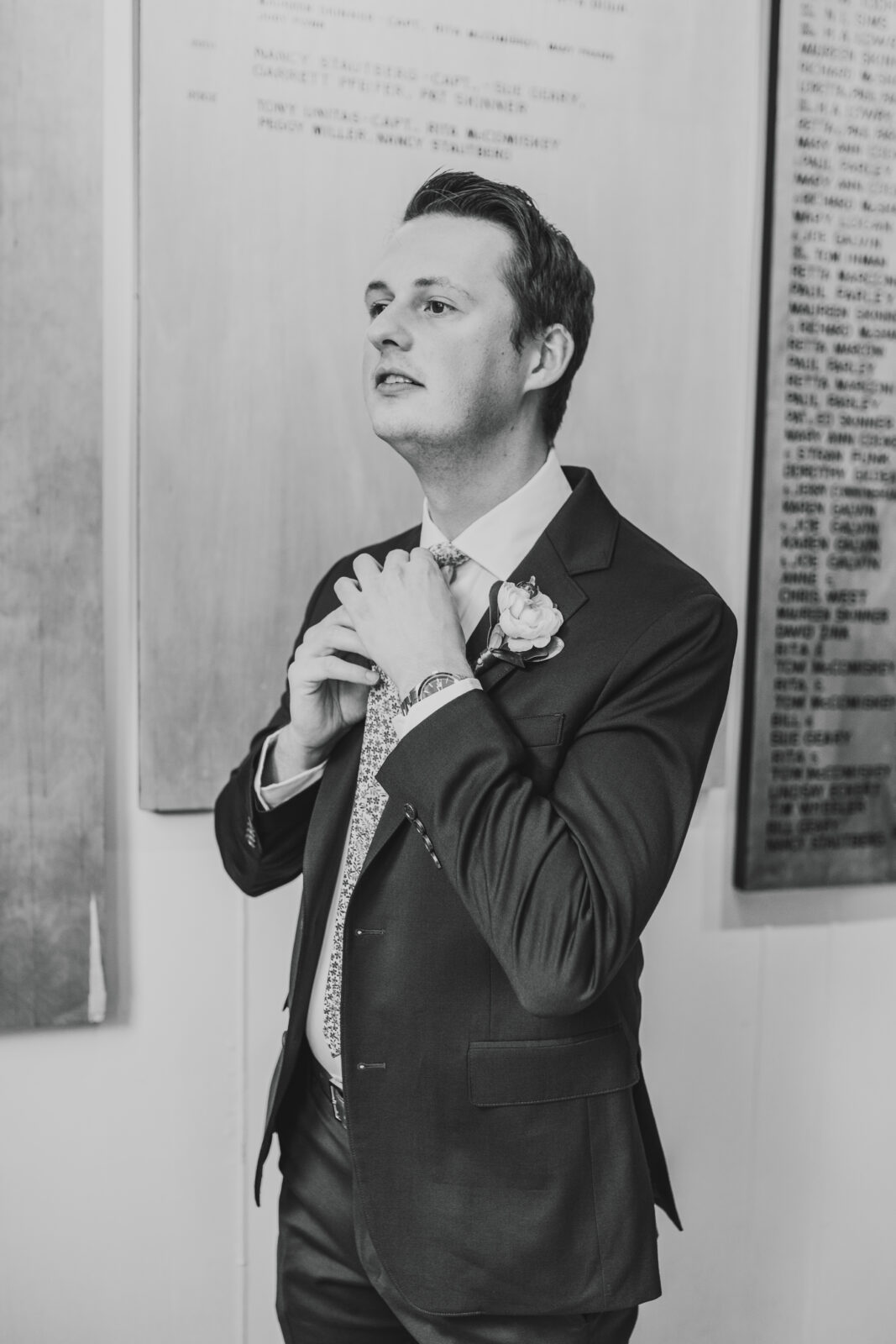 black and white classic wedding photography of groom adjusting his tie