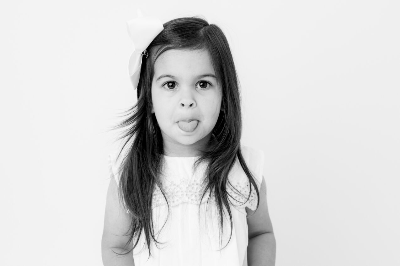 black and white candid photo of a young girl sticking out her tongue in a new Baltimore photography studio
