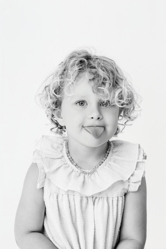 black and white candid photo of a young girl sticking out her tongue in a new Baltimore photography studio