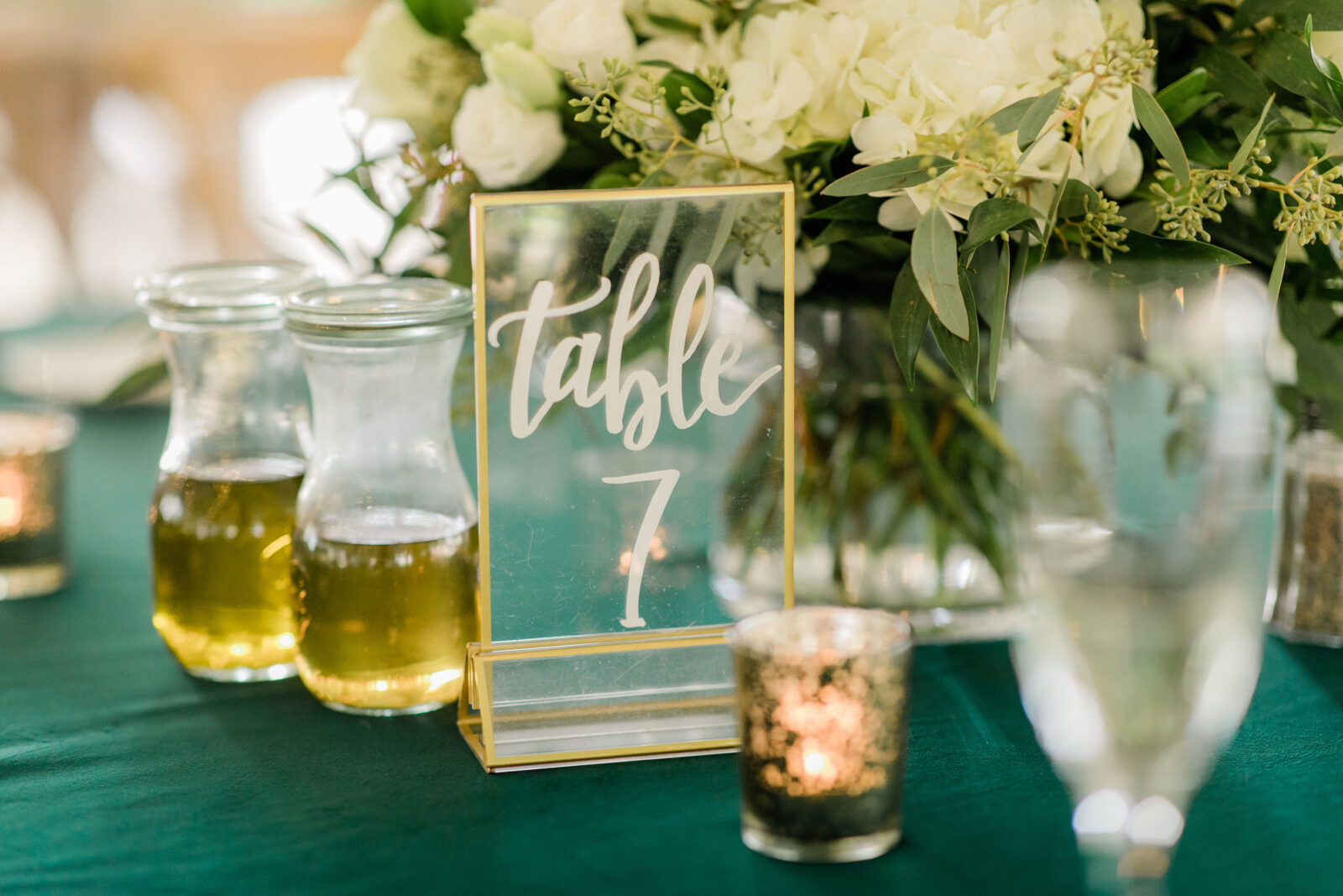 Reception table decorated with glass table number sign and florals
