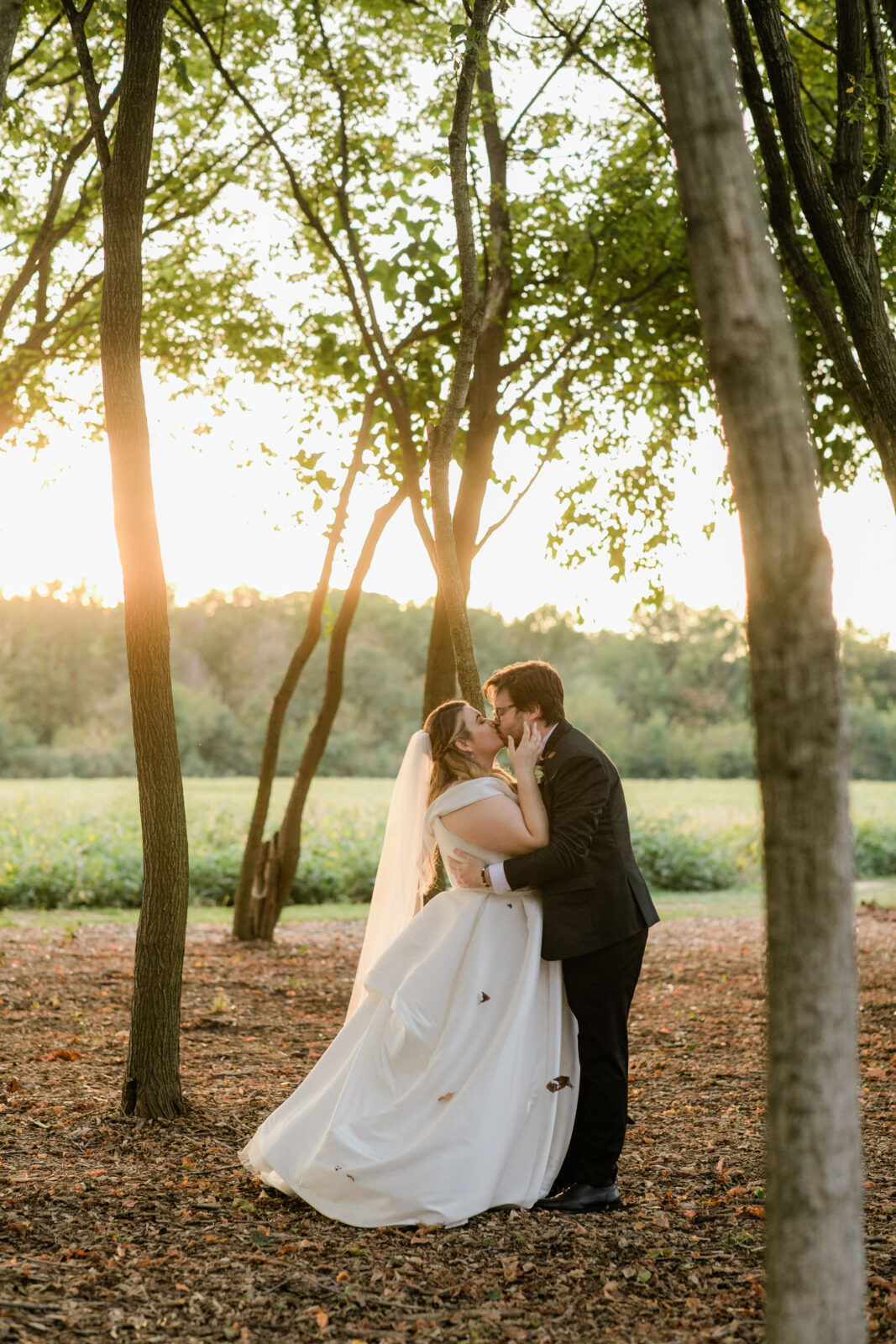Bride and groom sharing a kiss with autumn leaves on the grounds of Kent Island Resort