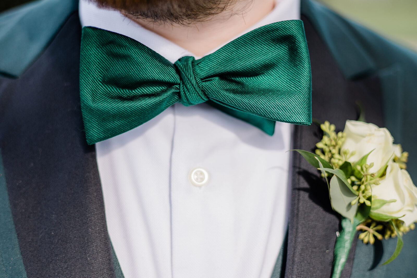 Close up of grooms emerald green bowtie and corsage