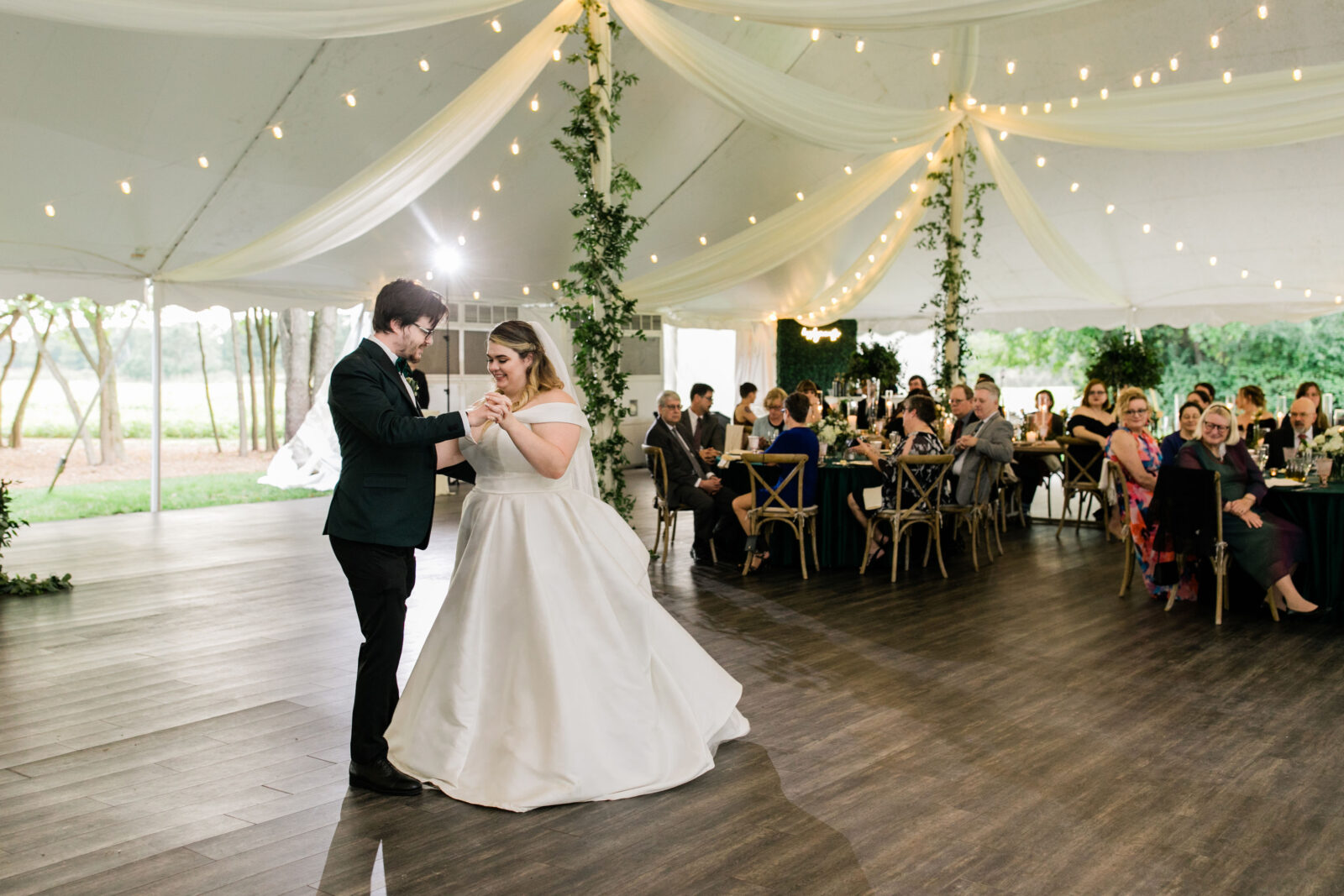 Bride and groom first dance under string lights inside the Kent Island Resort Pavilion