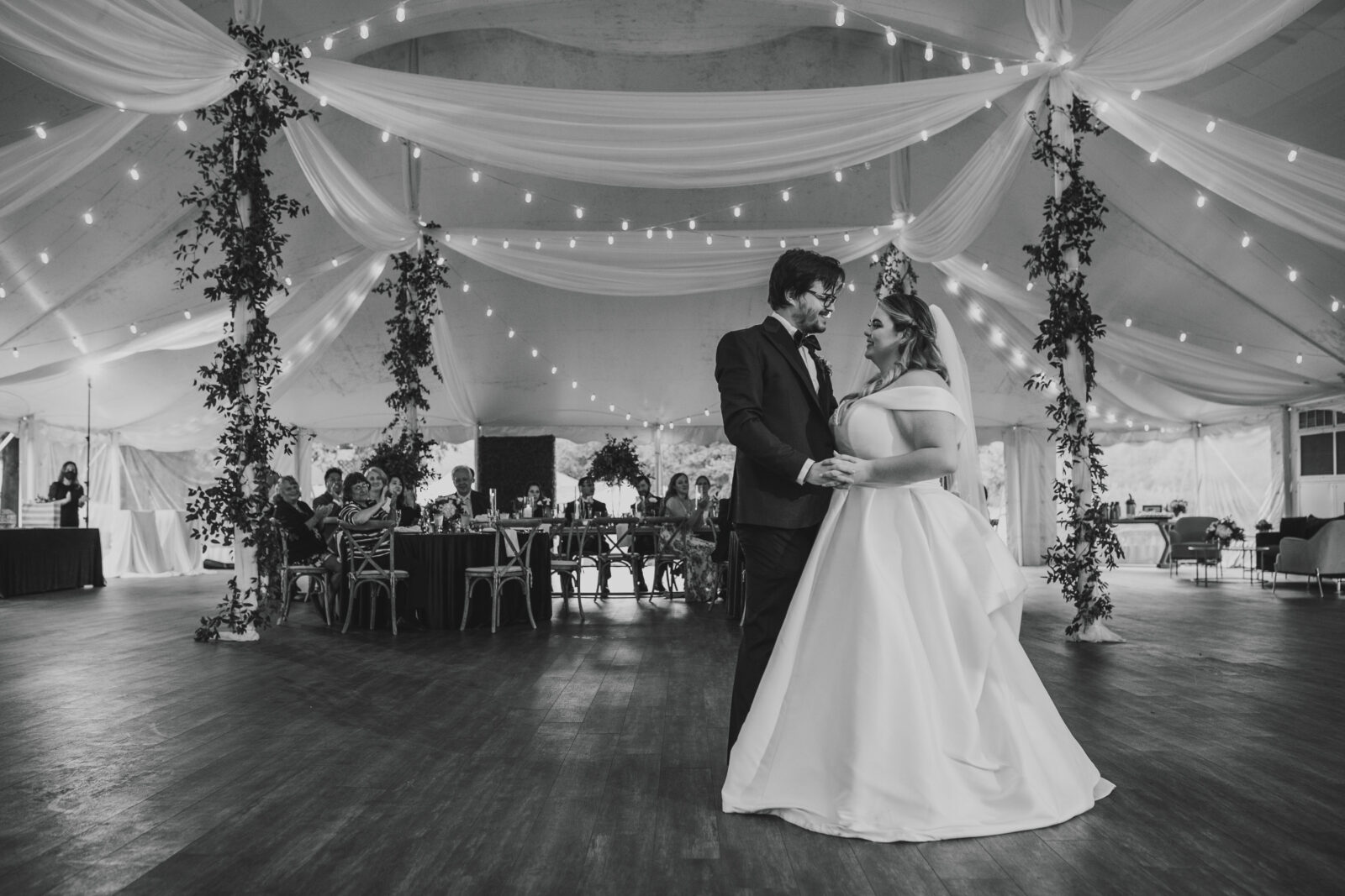 Bride and groom first dance under string lights inside the Kent Island Resort Pavilion