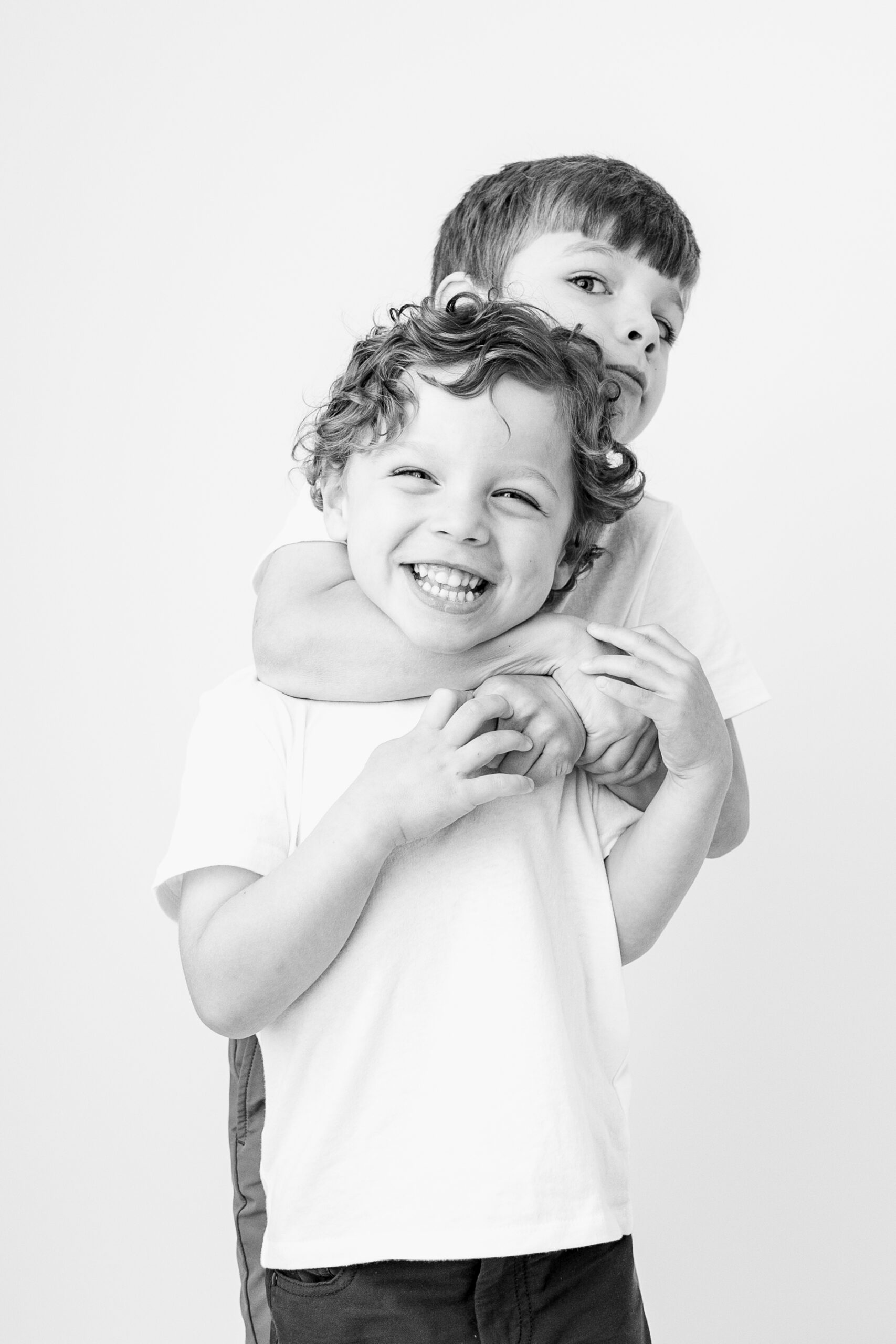Brothers playfully wrestling, one boy grinning straight at the camera