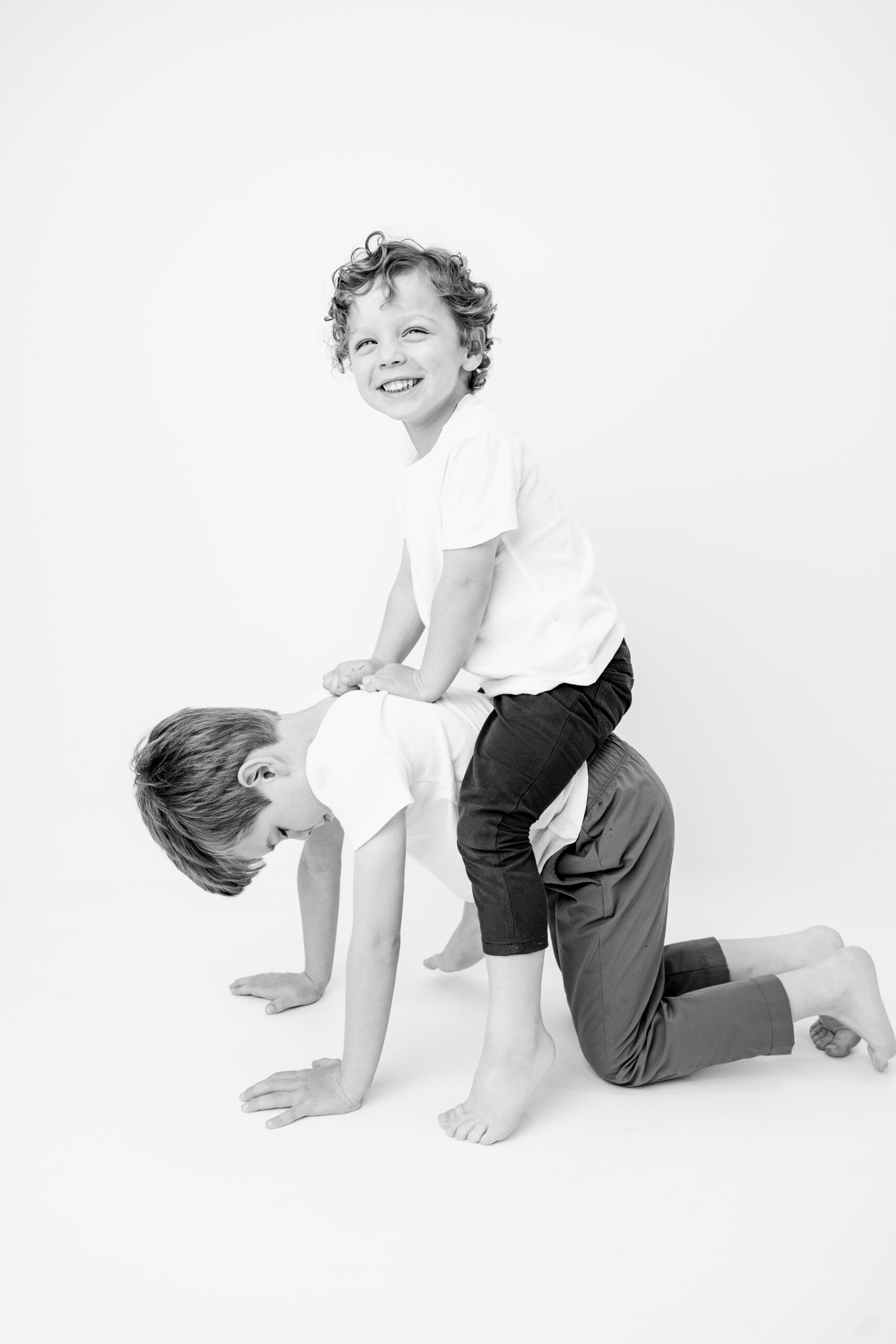 Brothers playfully wrestling on the studio floor, one boy grinning straight at the camera