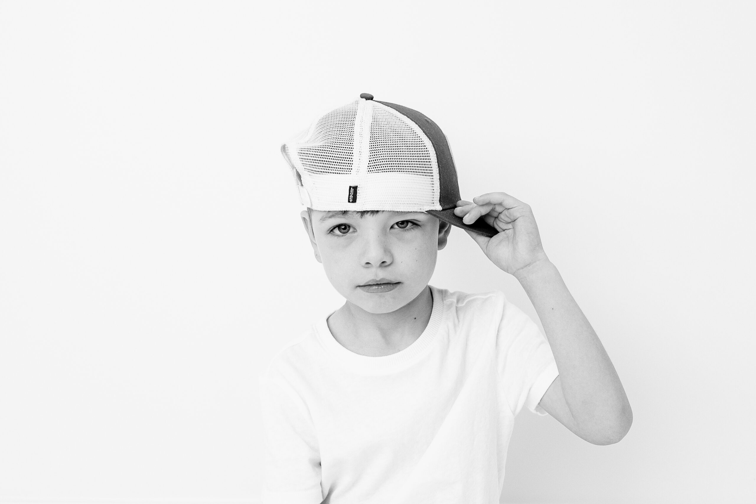 black and white image of a young boy in a sideways hat