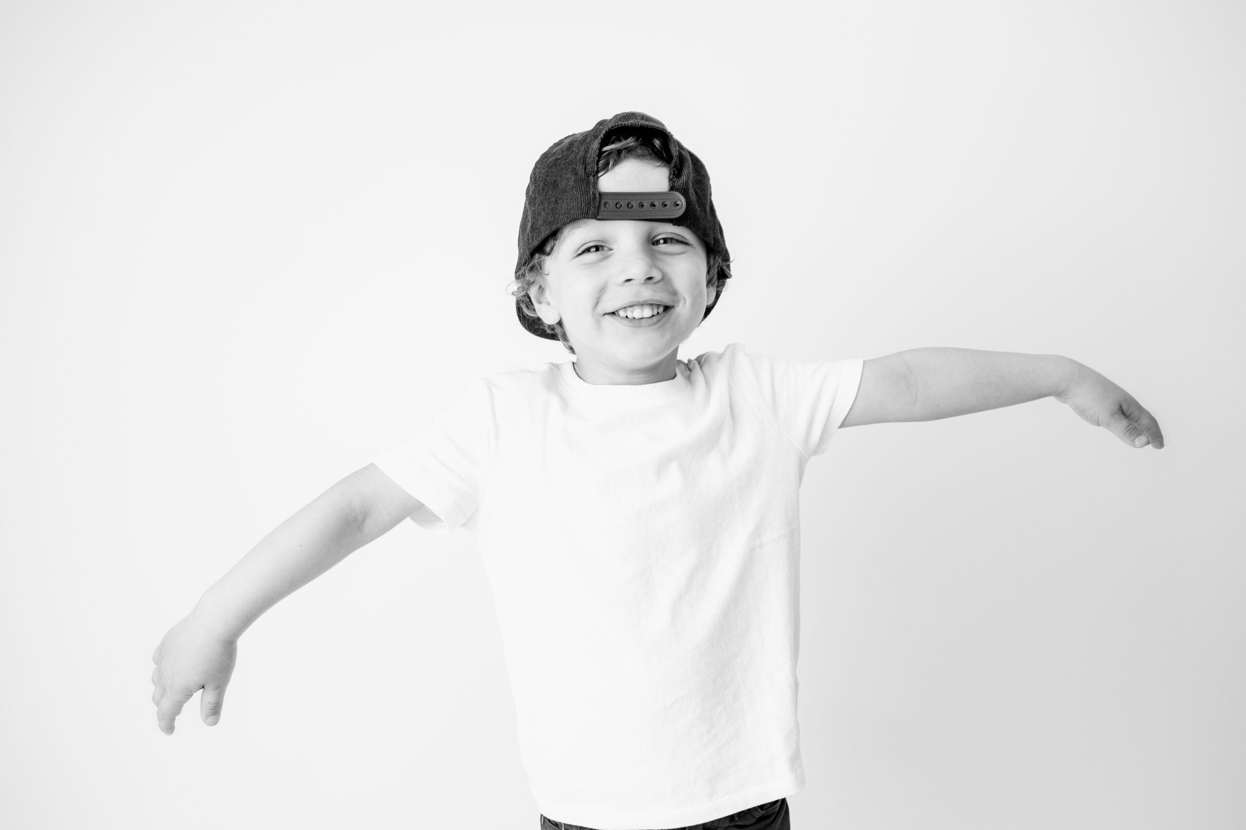 Boy wearing a backwards cap with hands on his cheeks, child photographer Baltimore portrait