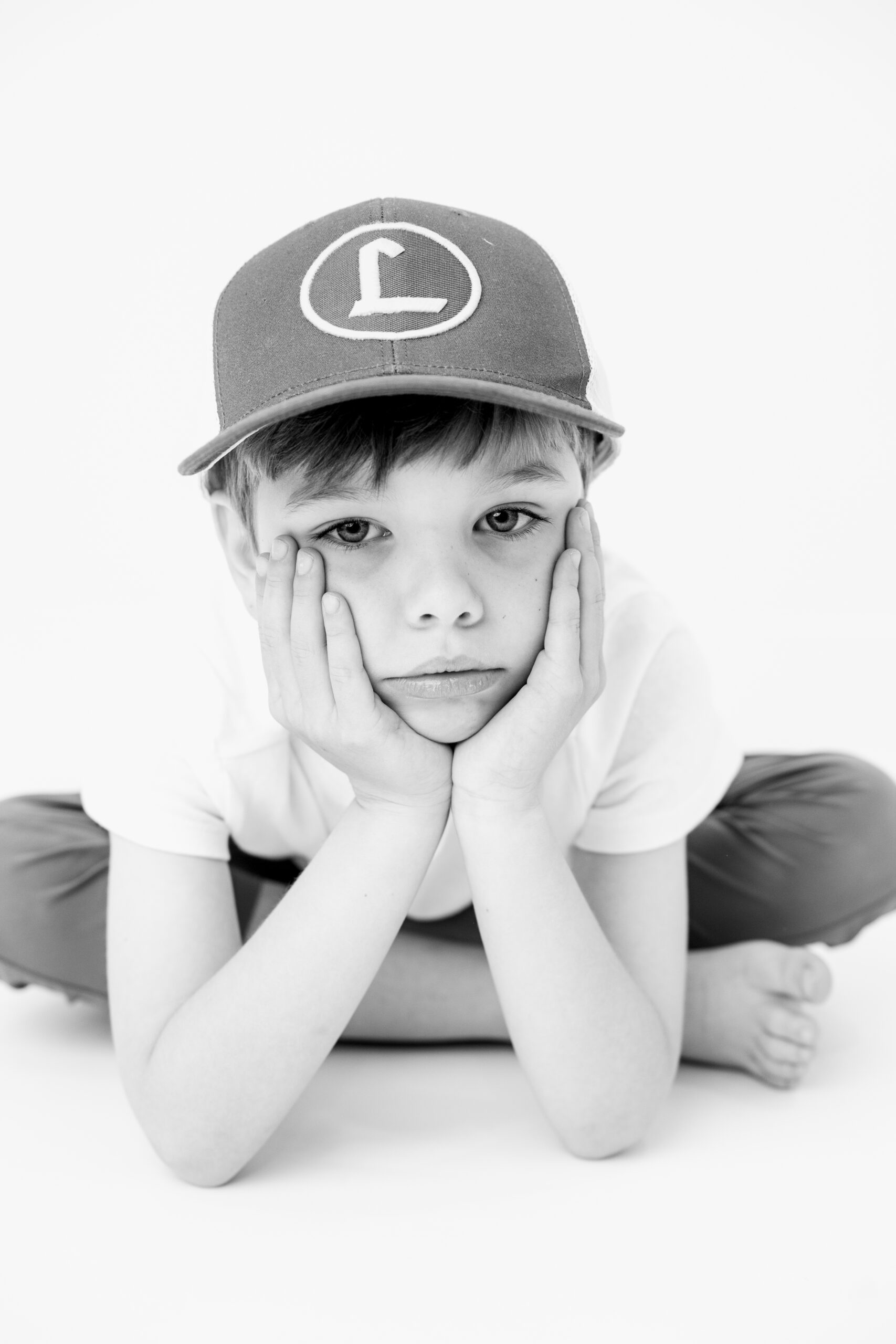 Boy wearing a cap with hands on his cheeks, child photographer Baltimore portrait