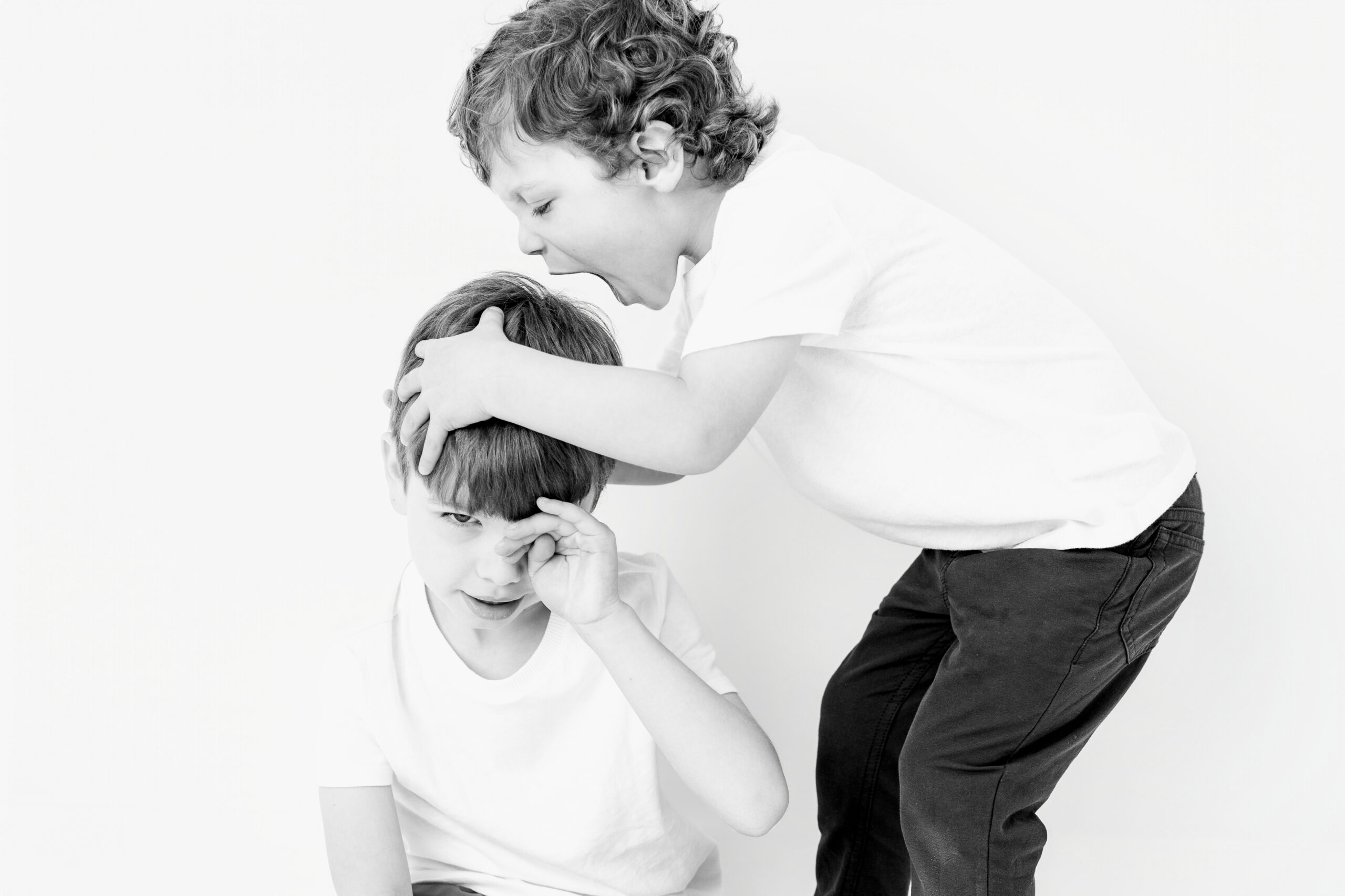 Brothers playfully wrestling on the studio floor, one boy grinning straight at the camera