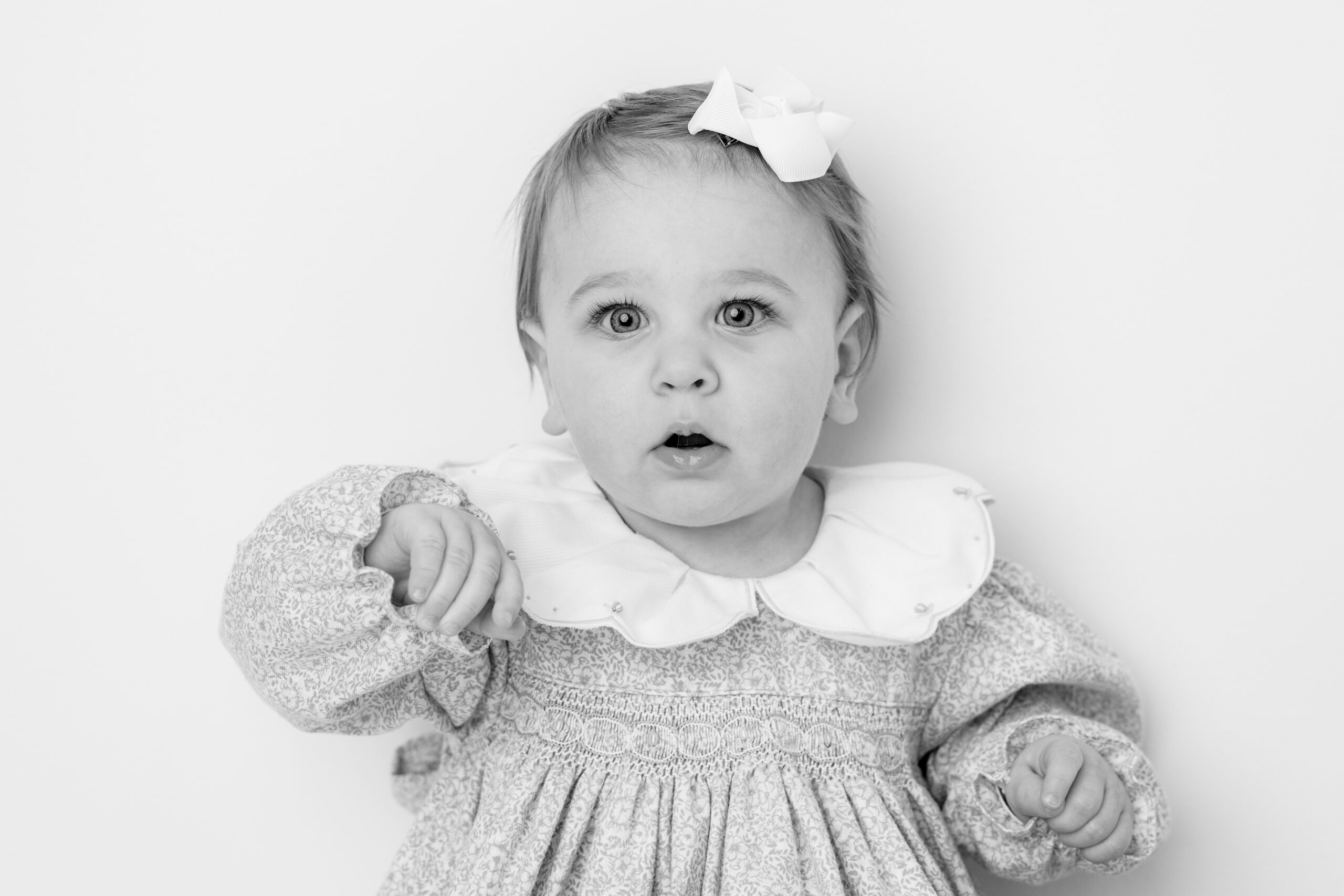 Baltimore children's photographer black and white portrait of a baby girl in a white bow and floral dress
