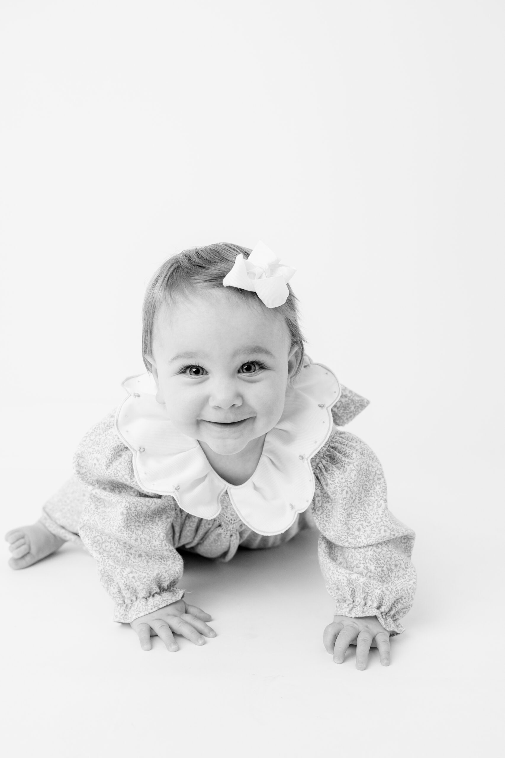 Child photographer Baltimore portrait of baby girl smiling with a white bow in her hair