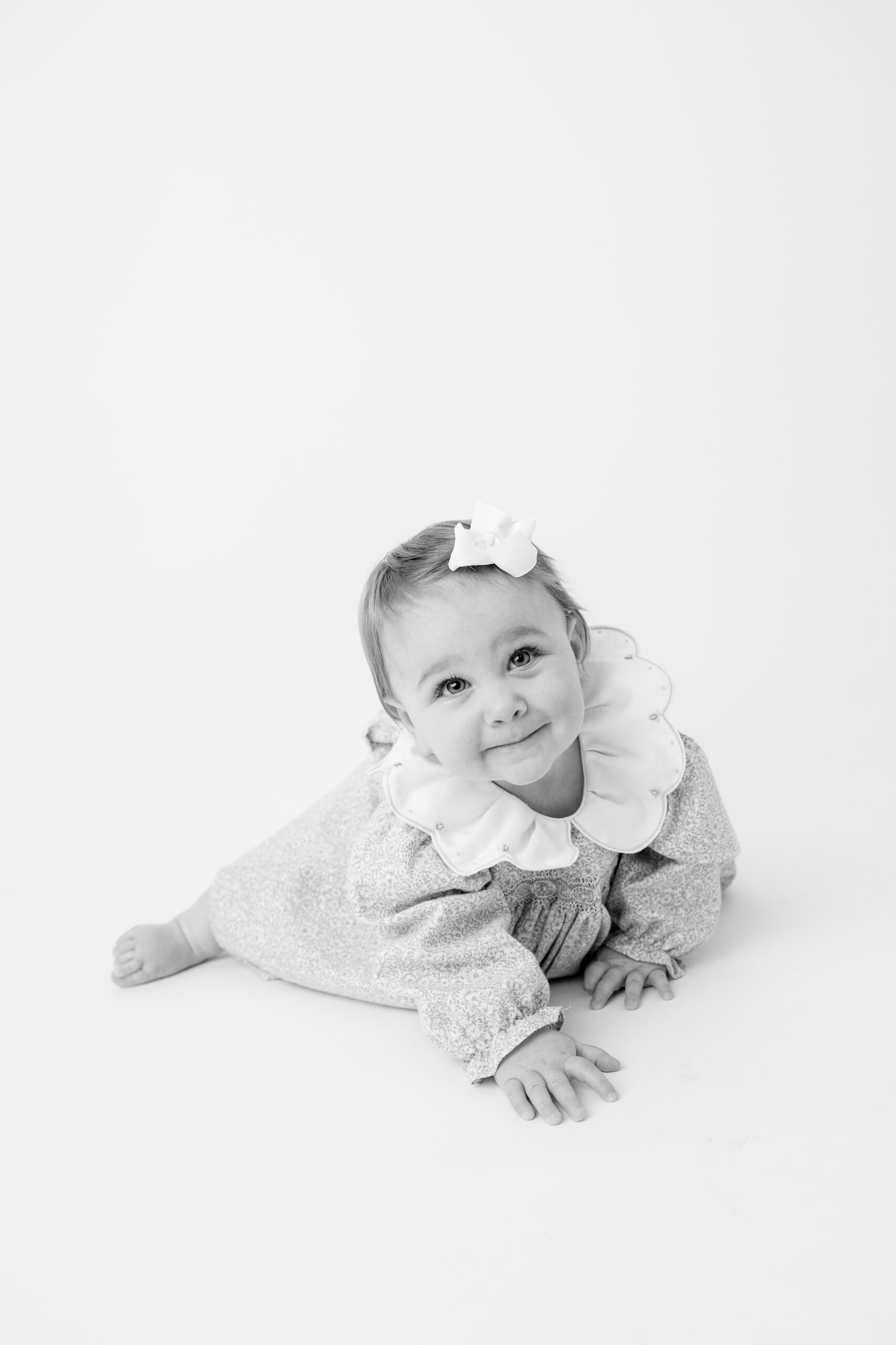Baby girl in floral smocked dress crawling toward the camera
