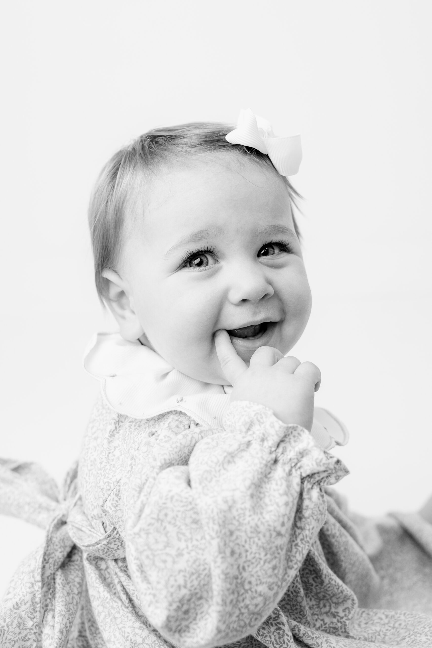 Baby girl in floral smocked dress laughing, child photographer Baltimore close up portrait