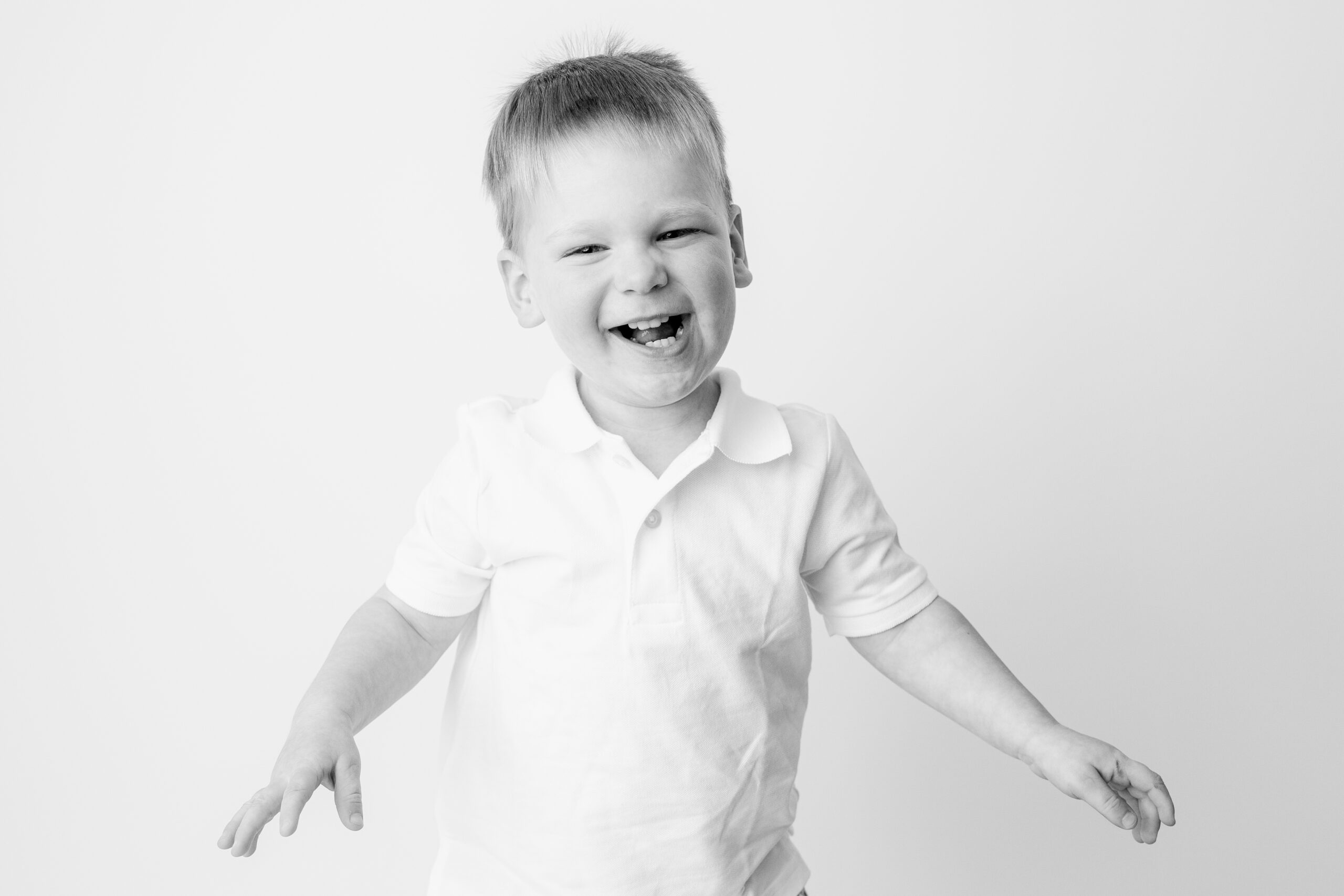 Baltimore children's photographer image of a toddler boy laughing with arms spread wide
