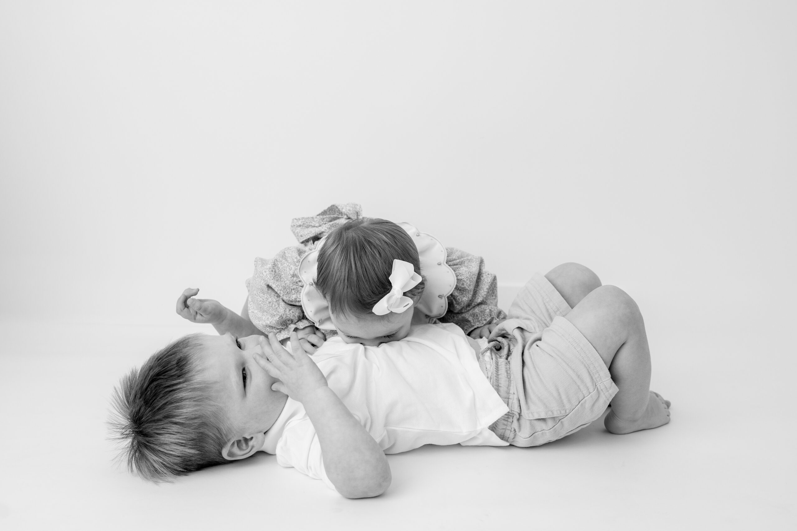 Two siblings sitting laying on the floor