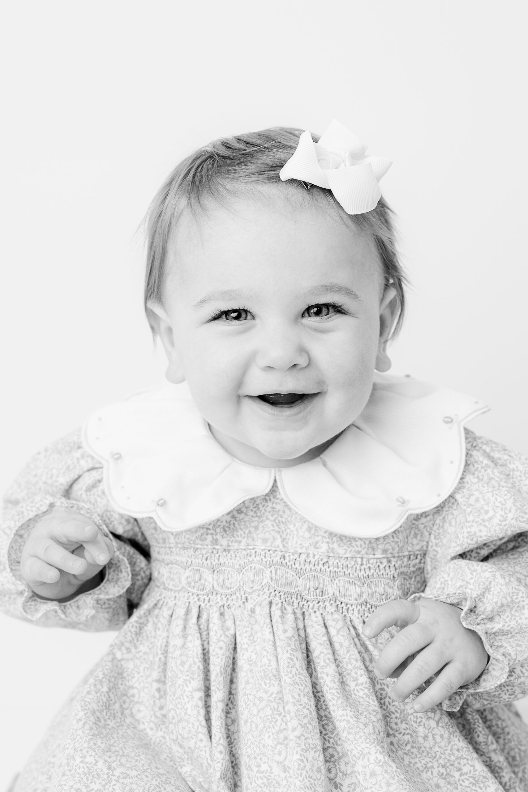 Baby girl in floral smocked dress laughing, child photographer Baltimore close up portrait