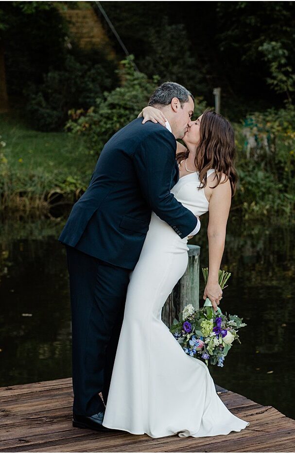 A bride and groom sharing a kiss on a doc in Annapolis