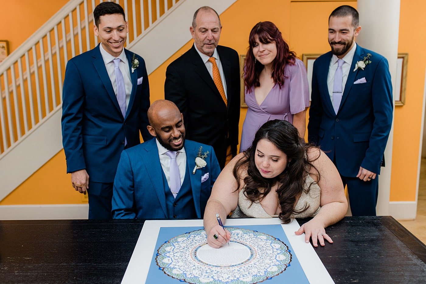 Bride and groom signing the ketubah on their wedding day